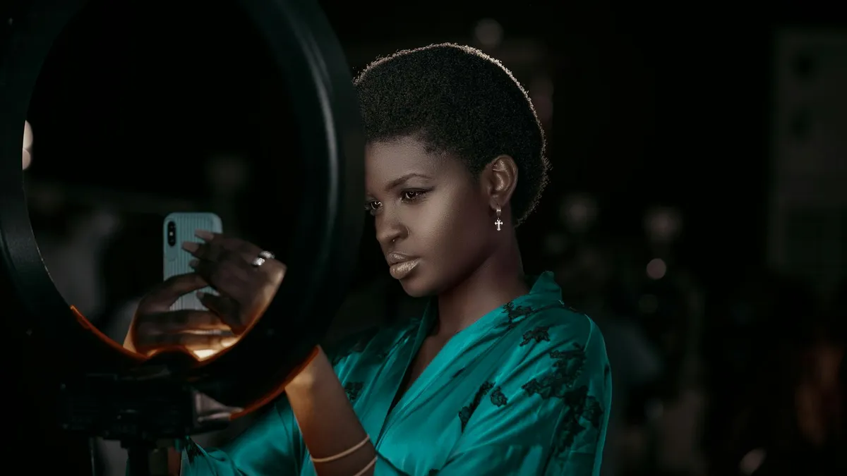 Créatrice de contenu noire aux cheveux courts naturels, face à un smartphone fixé sur une lampe annulaire