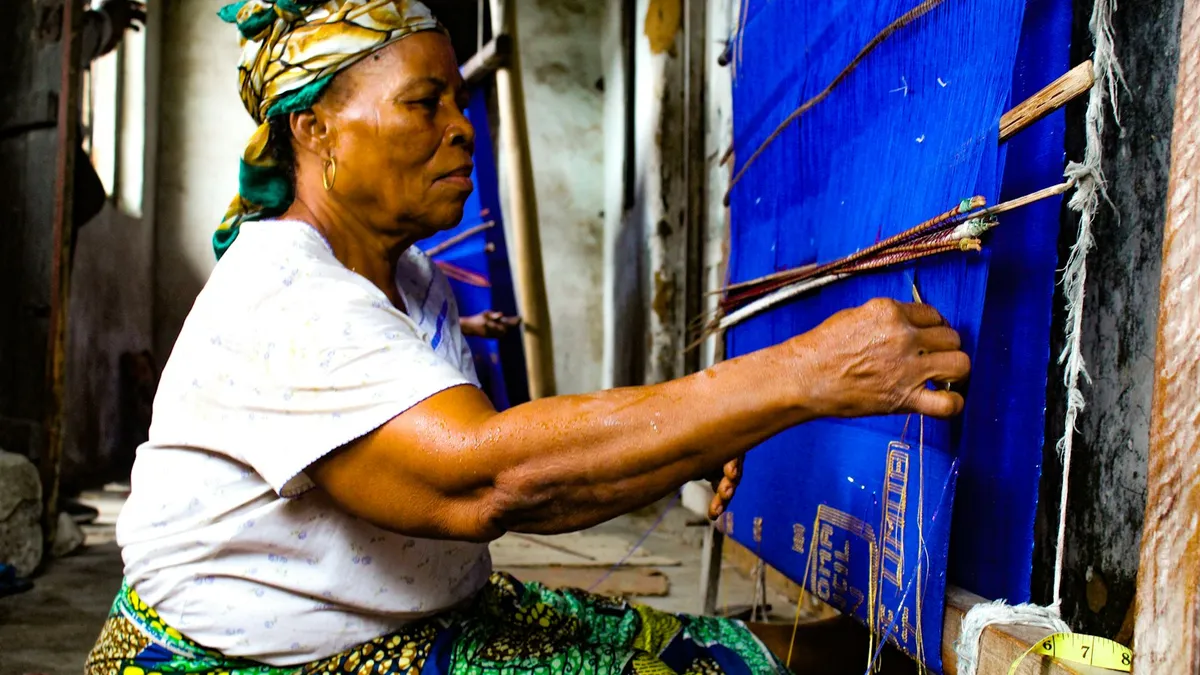 Tisserande d'Akwete, au Nigeria, travaillant un tissu bleu sur un métier à tisser