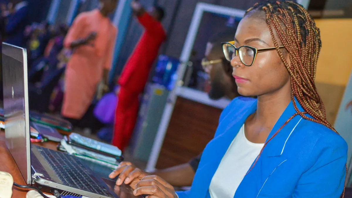 Femme aux tresses et aux lunettes, concentrée sur l'écran de son ordinateur portable